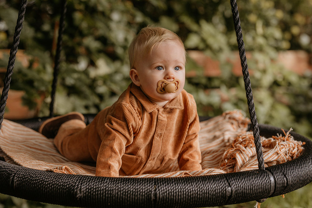 A young boy with a brown pacifier in his mouth