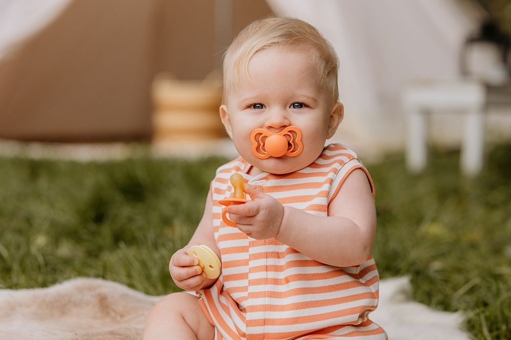 A young baby with a pacifier in its mouth