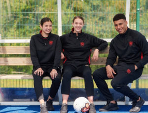 Three students sat down on a bench wearing Chadwick Teamwear P.E. kit