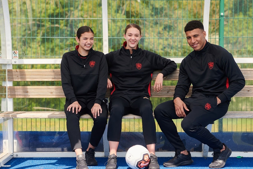 Three students sat down on a bench wearing Chadwick Teamwear P.E. kit