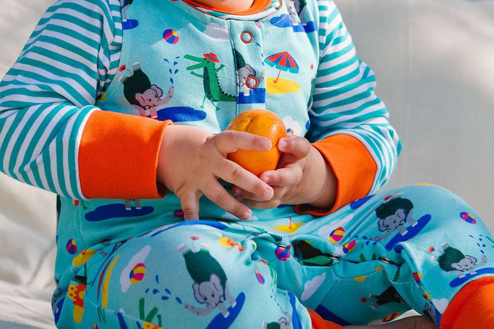 A young baby holding a satsuma