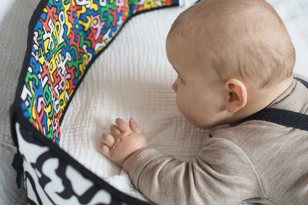 A young baby laid on a blanket next to a sensory strip