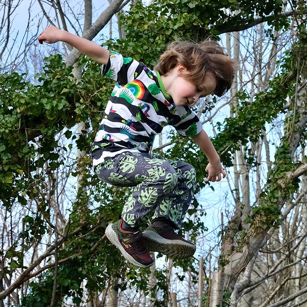 A boy in woodland jumping in the air wearing Pickbu