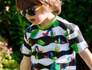 A young boy wearing sunglasses and a striped t-shirt with caterpillars on it by Pickbu