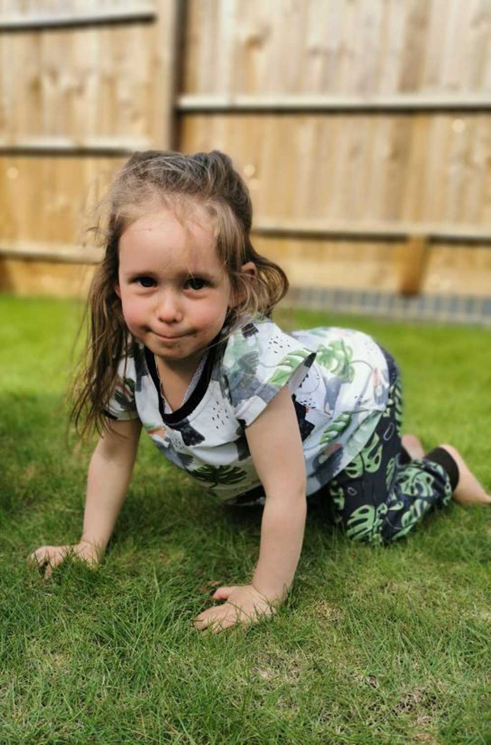 A young girl crawling on the floor in the garden