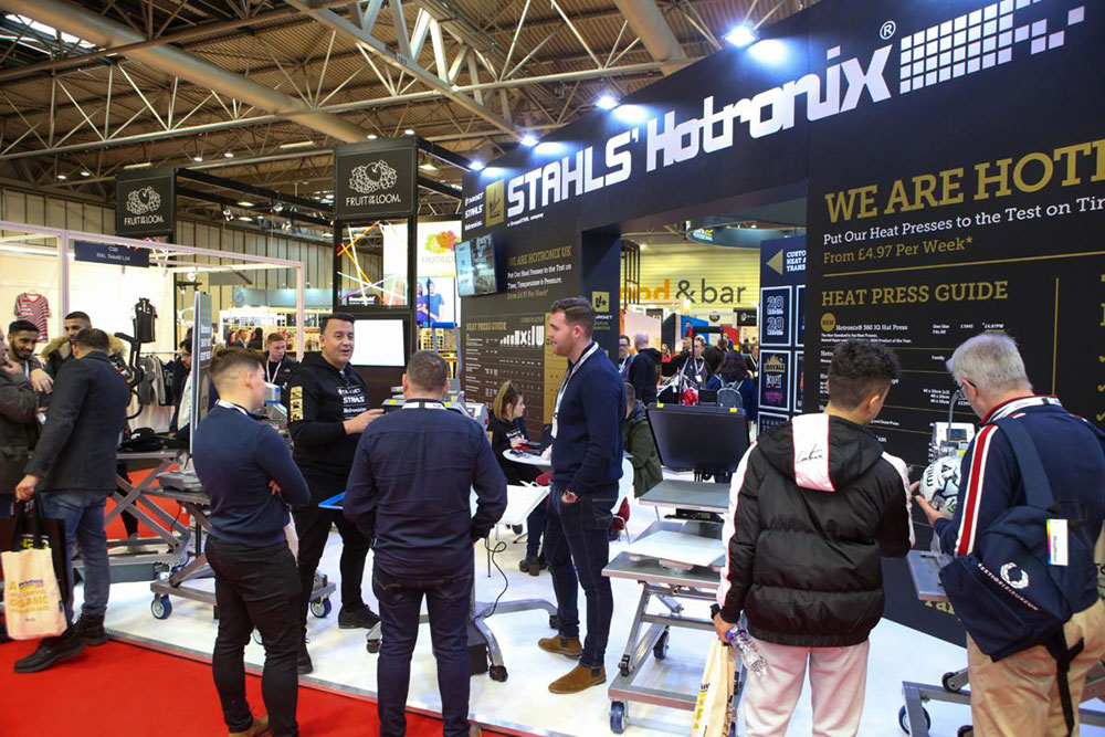 Visitors stood talking at one of the trade stands at Printwear & Promotion Live!