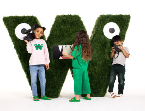Three children stood next to a large W logo wearing Whistles kidswear
