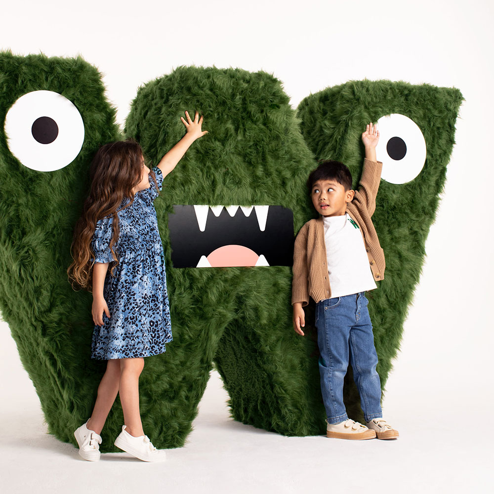 A boy and girl stood next to a large W logo