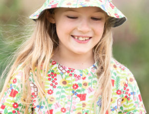 Girl wearing frugi accessories hat with summer print