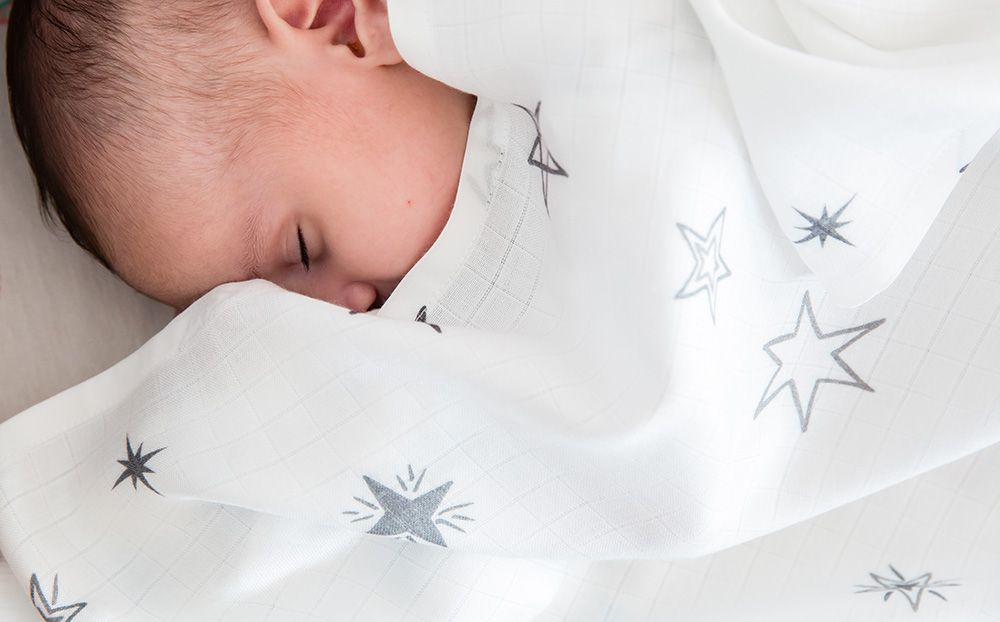 A baby asleep under a blanket with star pattern