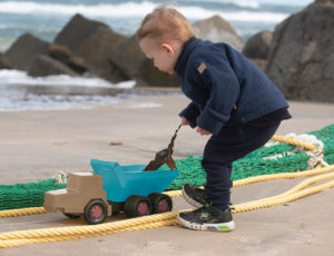 The young boy playing with a toy truck on the beach