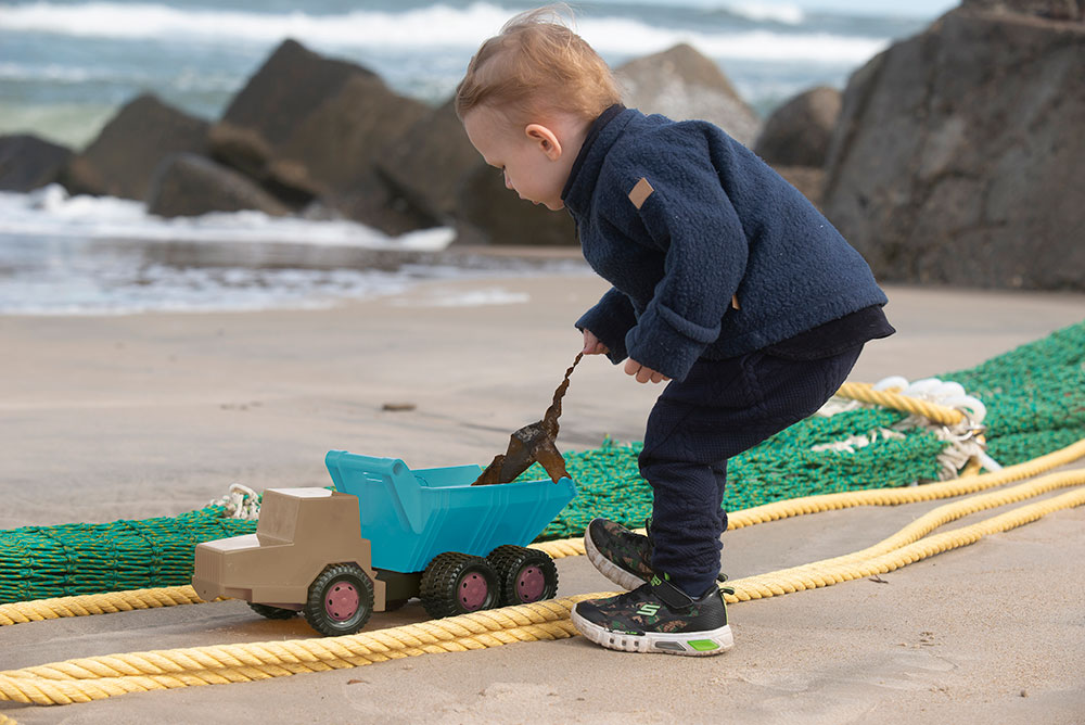 The young boy playing with a toy truck on the beach