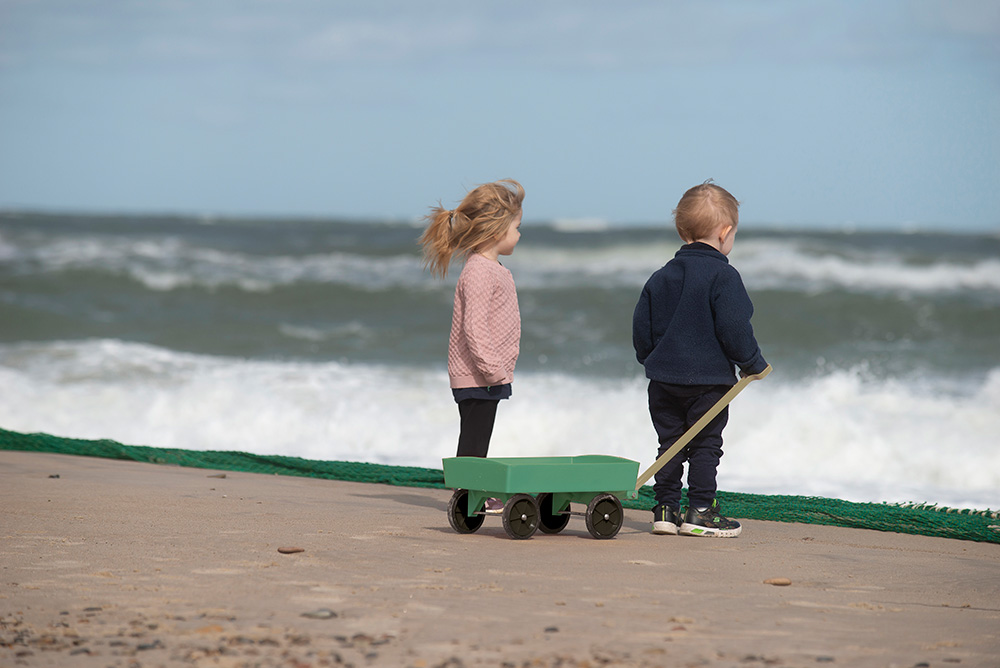 A young boy and girl stood on the beach next to each other looking out to sea