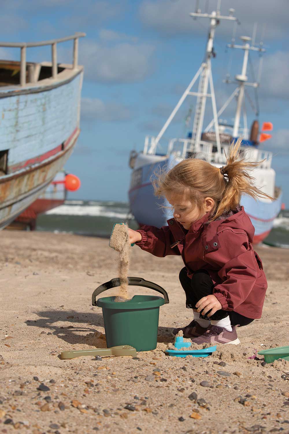 A young girl playing with a bucket and spade on the beach