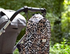 Leopard changing backpack hanging from the handle of a pushchair
