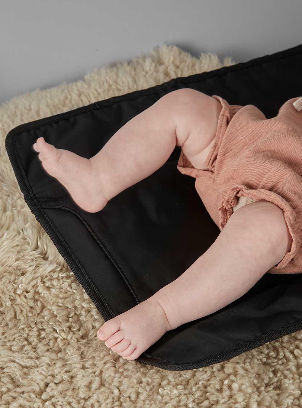A baby laid on a black changing mat
