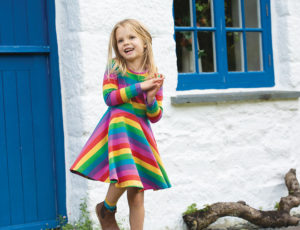 A young girl wearing a bright coloured striped dress