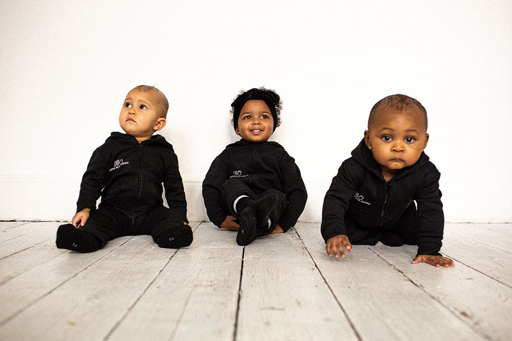 Three young children sat on the floor wearing black bodysuits