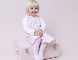 Girl sitting on a chest wearing Pastels & Co