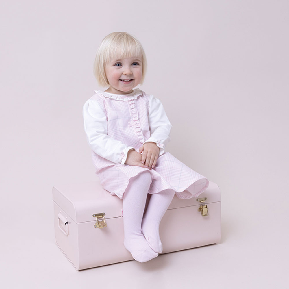 Girl sitting on a chest wearing Pastels & Co
