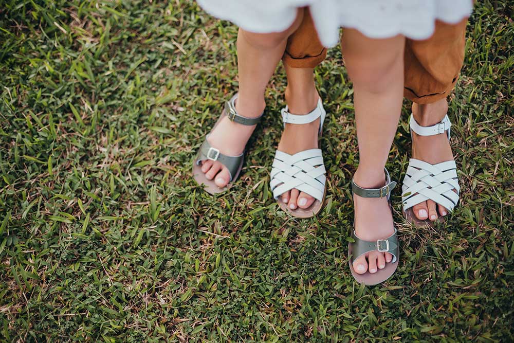 Two girls stood on grass wearing sandals