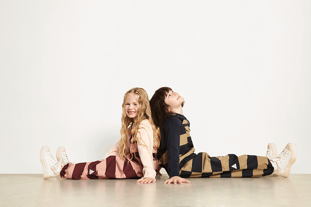 Two young girls sat back-to-back on the floor wearing TÖASTIE