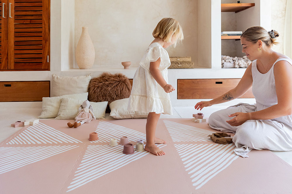 Mother and daughter playing on a pink playmat