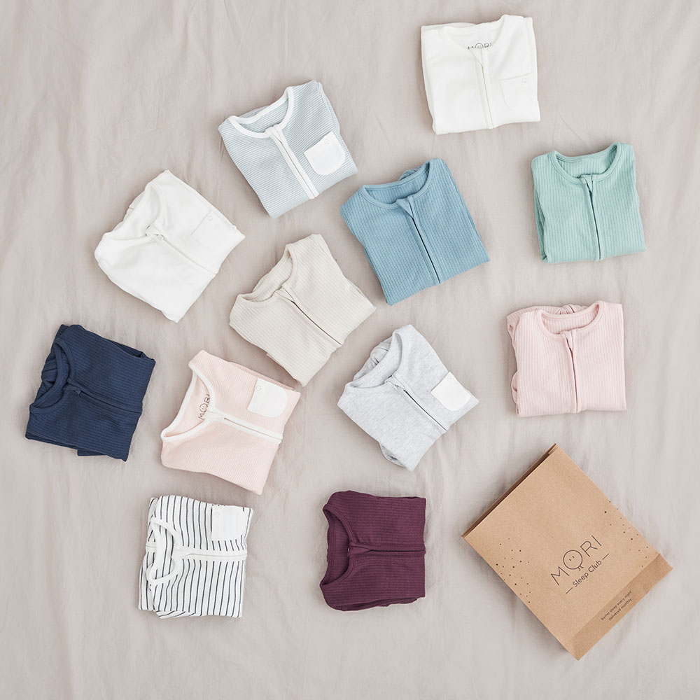 Baby sllep suits in variour colours folded neat and laid on the floor