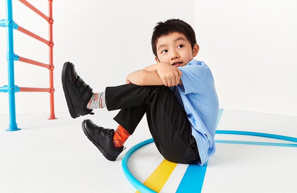 Young boy in school uniform sat on the floor