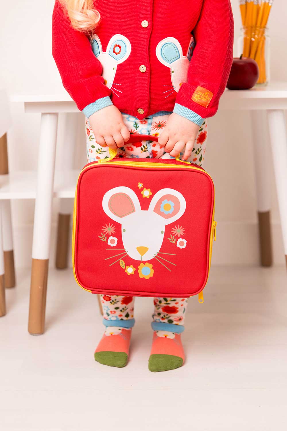 A boy in a red jumper holding a red lunchbox with mouse print on it