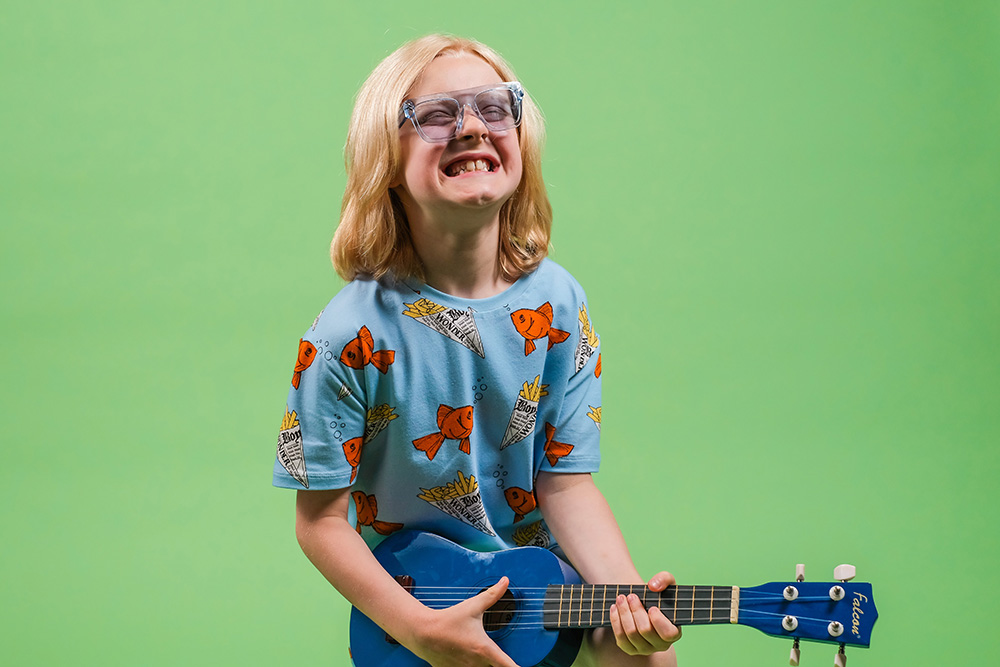 A young boy in a blue t-shirt playing a guitar