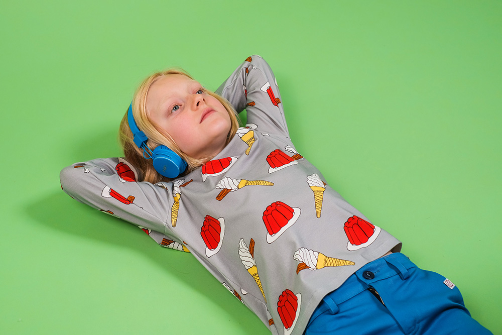 A young boy laid on the floor wearing a set of blue headphones