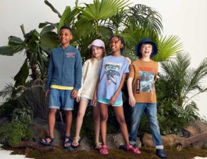Four children stood together wearing clothing with dinosaur prints