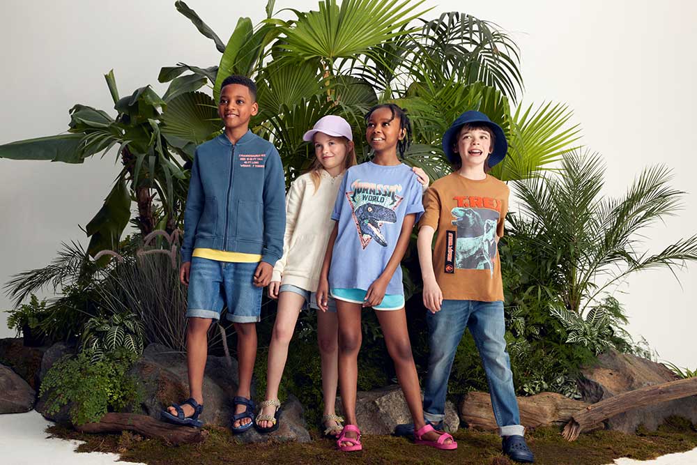 Four children stood together wearing clothing with dinosaur prints