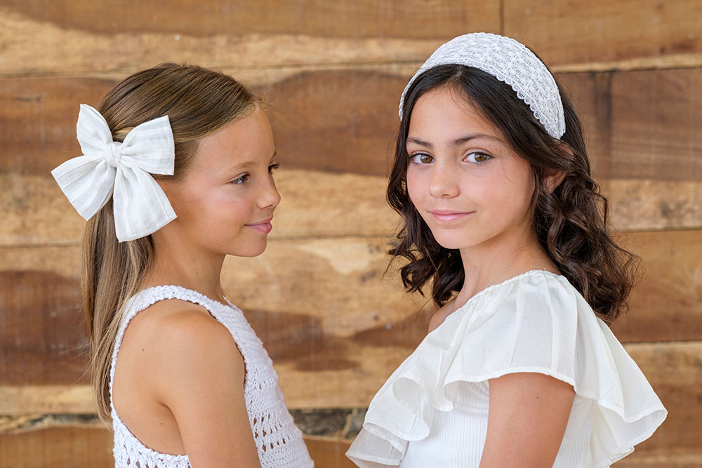 Two girls stood next to each other wearing white dresses