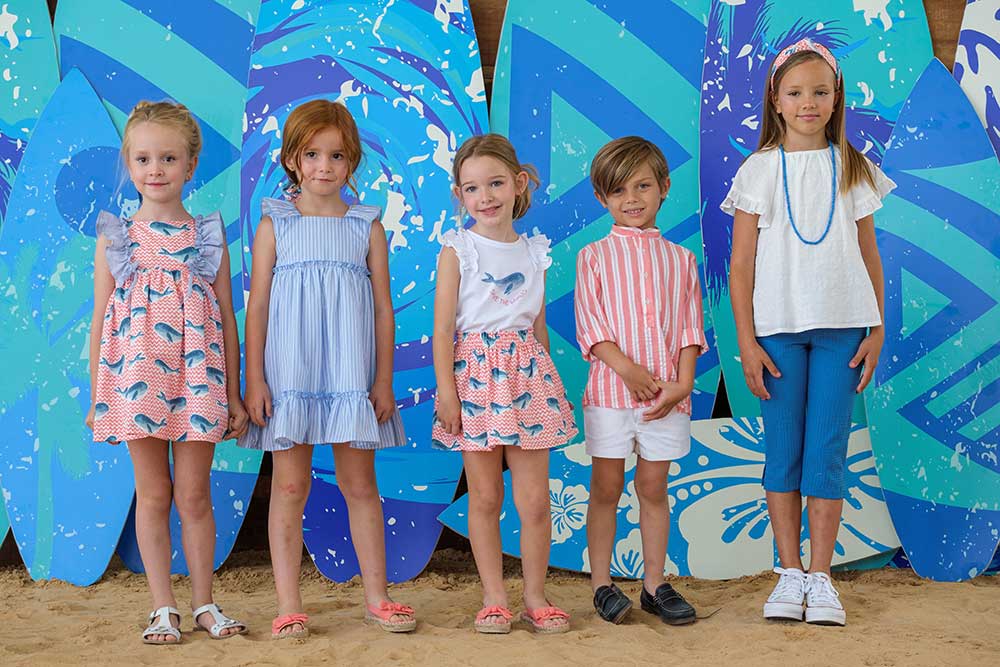 Five boys and girls standing in front of six surf boards