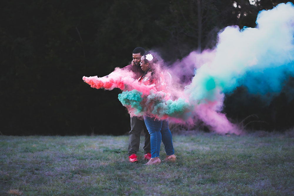 A man and woman letting a pink and blue flare off