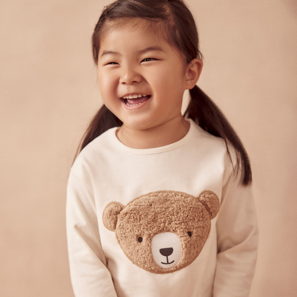 Young girl in beige jumper with Autumn Bear on front