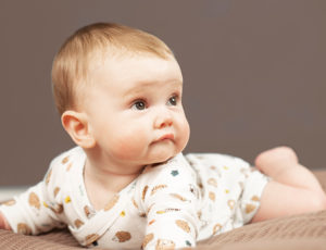 A young baby crawling on a blanket