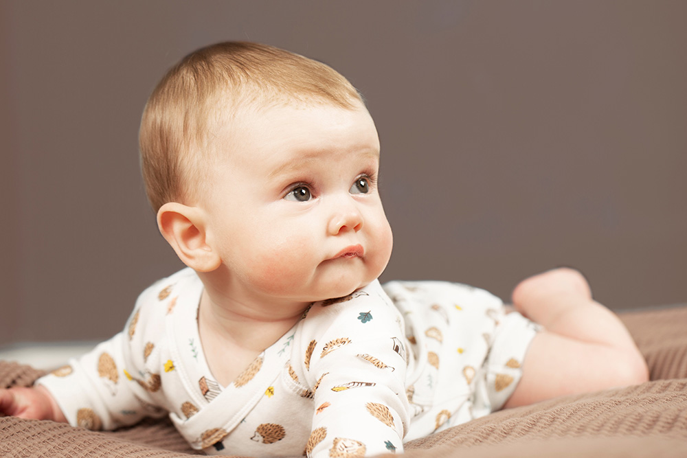 A young baby crawling on a blanket