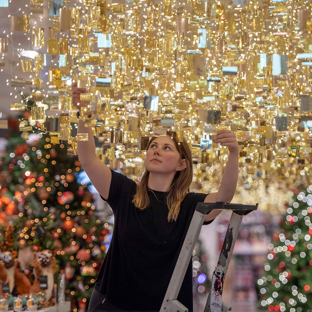 Woman hanging Christmas decorations in a John Lewis store