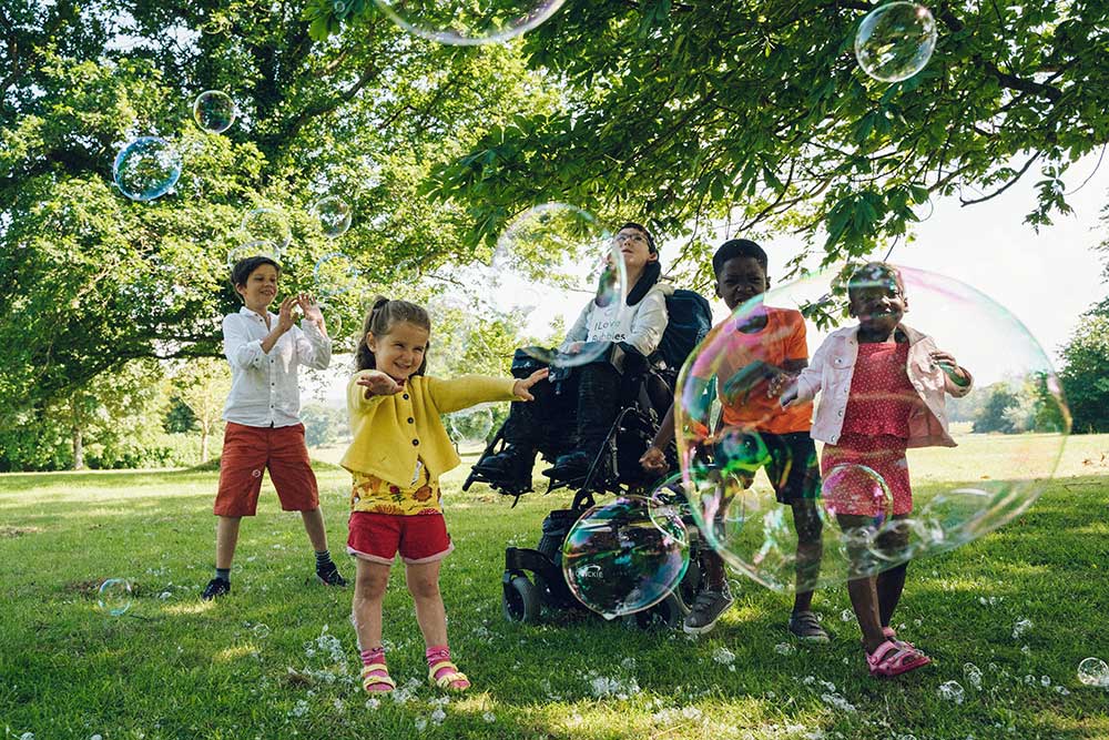 Five young kids blowing bubbles in the park