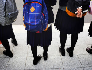 Four school kids in school uniform with a backpack on their back
