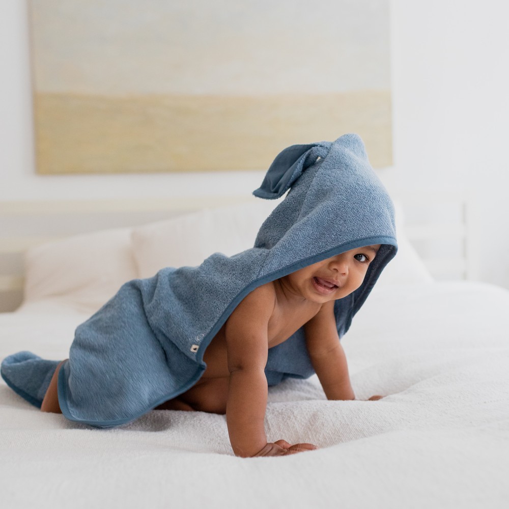 Baby crawling wearing a blue hooded towel with ears on