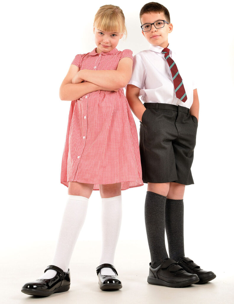 Two children stood side by side wearing school uniform 