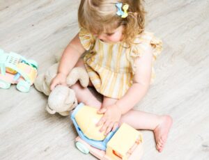 Girl sat on the floor playing with a toy truck