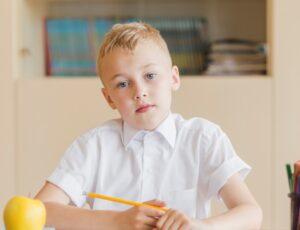 Boy sat at a school desk wearing school uniform