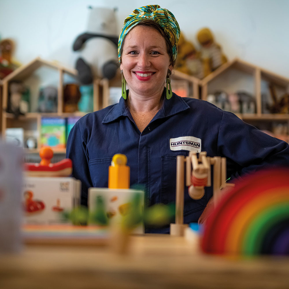 Women stood behind a shelf with wooden toys on 