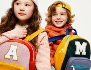 Girl and boy holding rucksacks with initials on the front of them