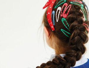 Back of a girl's head with long brown hair covered in school hair clips and a hairband